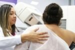 Técnica acompanha paciente durante exame de mamografia