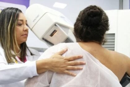 Técnica acompanha paciente durante exame de mamografia