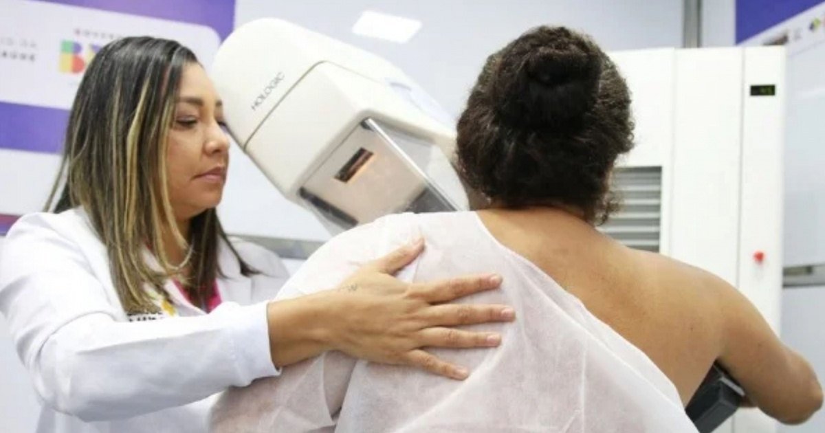 Técnica acompanha paciente durante exame de mamografia