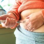 Pessoa aplicando medicamento injetável na barriga
