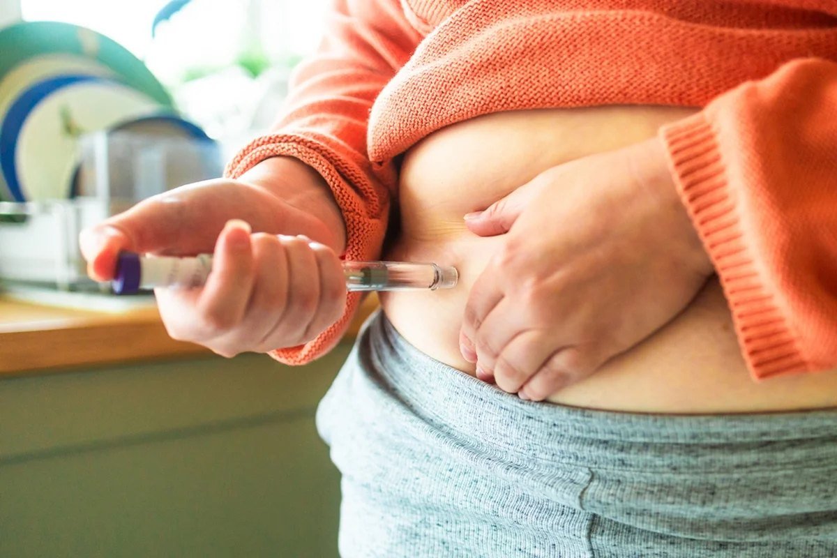 Pessoa aplicando medicamento injetável na barriga