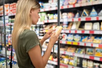 Consumidora lendo o rótulo de um produto no supermercado