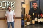 Sommelier Fred Poli em seu wine bar ao lado de garrafas de vinho