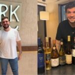 Sommelier Fred Poli em seu wine bar ao lado de garrafas de vinho