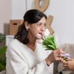 Mulher sentindo o perfume de um buquê de flores