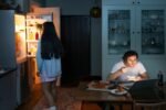 Pessoa comendo de madrugada na cozinha iluminada pela geladeira