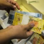 Mãos contando cédulas de real