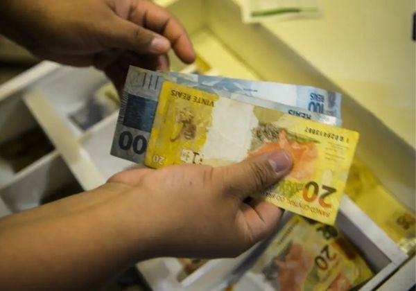 Mãos contando cédulas de real