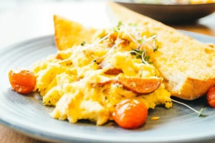 Prato de ovos mexidos cremosos com tomates ao lado