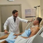 Médico atende paciente em leito de hospital em Salvador