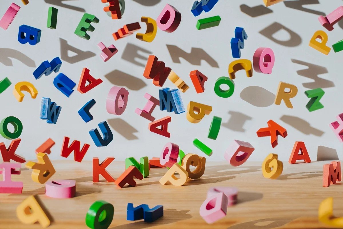 Letras coloridas de brinquedo espalhadas sobre a mesa