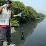 Pesquisador coleta amostra de água em rio urbano