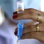 Profissional de saúde segura seringa e frasco de vacina