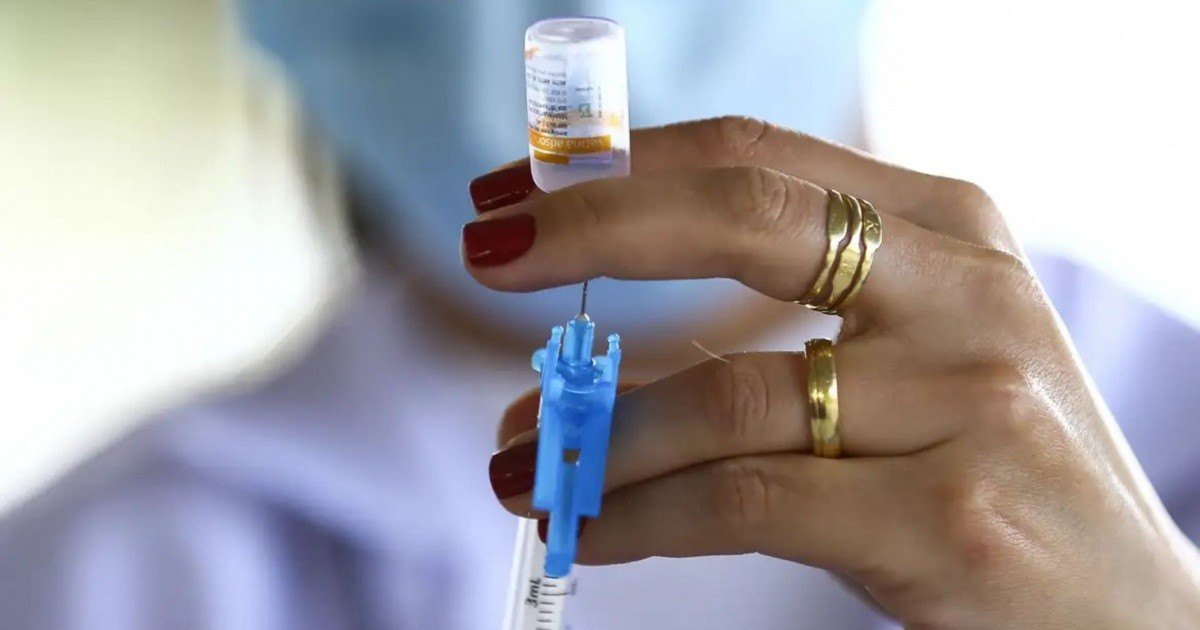 Profissional de saúde segura seringa e frasco de vacina