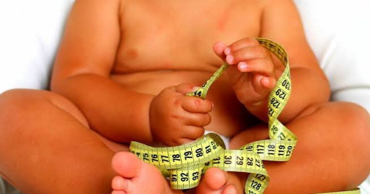 Barriga de criança com fita métrica enrolada na mão