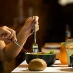 Pessoa fazendo refeição com legumes e pão