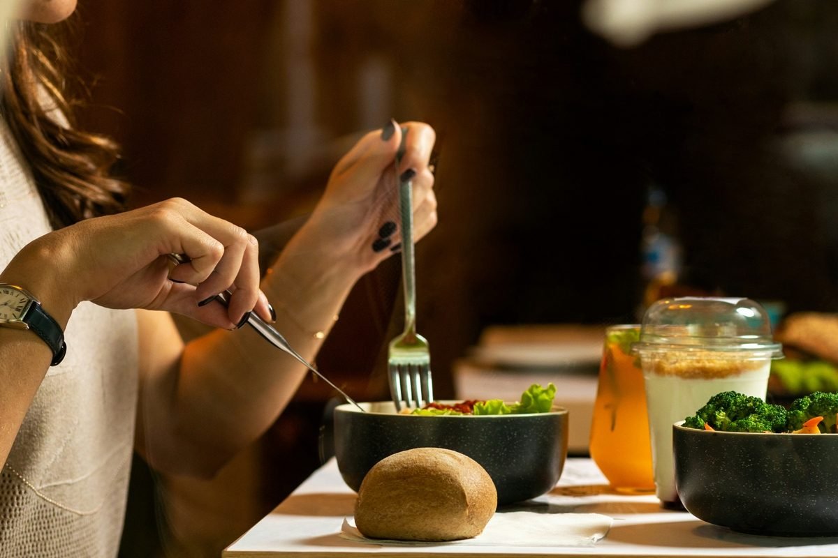 Pessoa fazendo refeição com legumes e pão