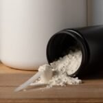 Pote de creatina em pó aberto sobre a mesa