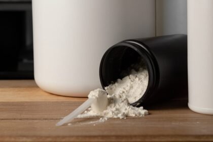 Pote de creatina em pó aberto sobre a mesa