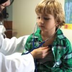 Médica mede a pressão de menino em consultório
