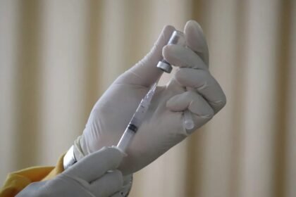 Mão com luva segura seringa com dose de vacina