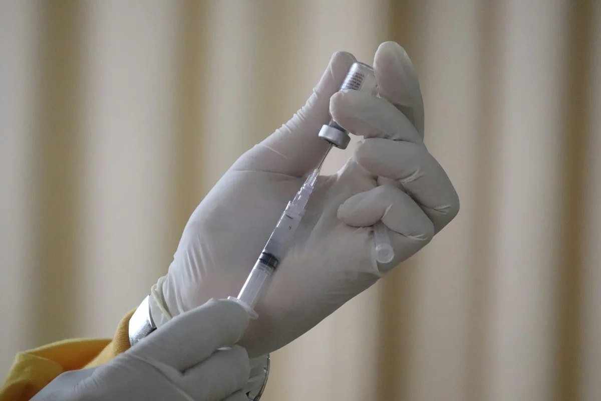 Mão com luva segura seringa com dose de vacina